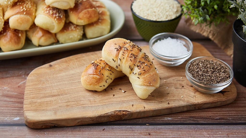 Domaće kiflice sa semenkama na drvenoj dasci.