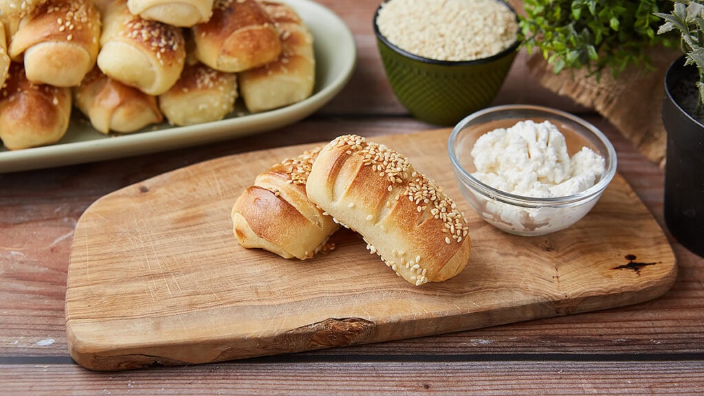 Sveže domaće kiflice bez aditiva sa sezamom na drvenoj dasci.